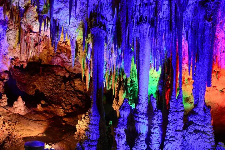 Stunning stalactites and stalagmites in Venetsa Cave illuminated by colorful lights.